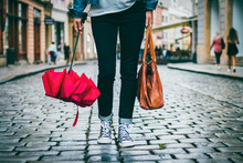 Woman Holding Leather Bag And Red Umbrella And She Is Walking On The Street After Rain 