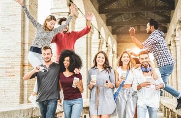 Wall Mural - Happy students having fun in old city center - Young people at university break enjoying time together - Youth and positive mood with friends concept - Focus on right women holding coffee paper cup