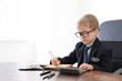 © Africa Studio - Cute little boy counting money at table indoors