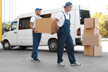Male Movers Unloading Boxes From Van Outdoors