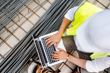 Wall Mural - Construction engineer writing report on laptop at construction site