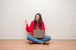 © Krakenimages.com - Young brunette woman sitting on the floor using laptop and smartphone screaming proud and celebrating victory and success very excited, cheering emotion