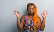 © Krakenimages.com - Young african american woman over grey grunge wall wearing orange braids relax and smiling with eyes closed doing meditation gesture with fingers. Yoga concept.