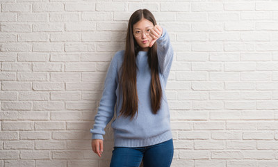 Poster - Young Chinise woman over white brick wall looking unhappy and angry showing rejection and negative with thumbs down gesture. Bad expression.