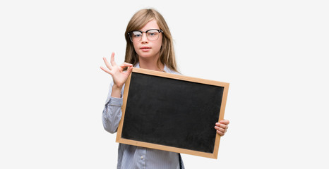 Sticker - Young blonde child holding blackboard doing ok sign with fingers, excellent symbol