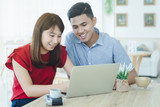 Fototapeta Tulipany - Happy asian couple using computer at home