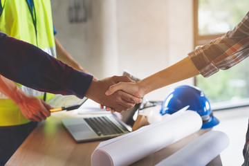 construction worker and contractor. Client shaking hands with team builder in renovation site.