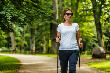 Wall Mural - Nordic walking - middle-aged woman working out in city park