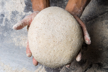 Male hands kneading dough on sprinkled