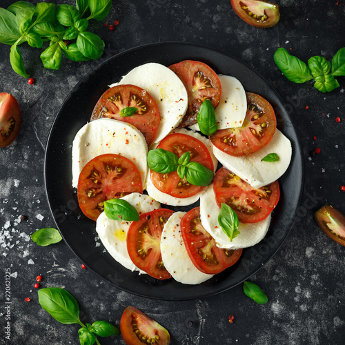 Fotomural Caprese salad with tomatoes, mozzarella cheese and fresh basil leaves in a black plate