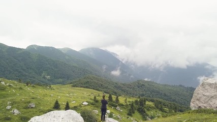 Wall Mural - tourist woman standing on mountain edge and watching on green valley drone view