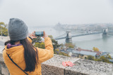 Fototapeta  - woman taking picture of old european city from the hill