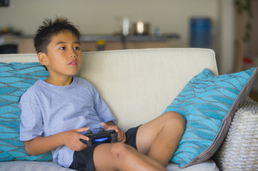 Canvas Print -  Latin young child 8 years old excited and happy playing video game online holding remote controller enjoying having fun sitting on couch in internet gaming