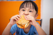 Leinwandbild Motiv Asian Chinese little girl eating burger