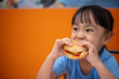 Leinwandbild Motiv Asian Chinese little girl eating burger