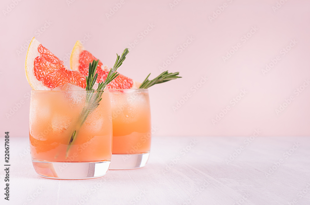 Summer cold cocktail with ice cubes, juice and slices grapefruit on pastel pink background. - obrazy, fototapety, plakaty 
