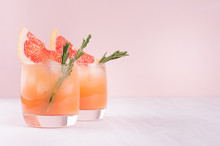 Summer Cold Cocktail With Ice Cubes, Juice And Slices Grapefruit On Pastel Pink Background.
