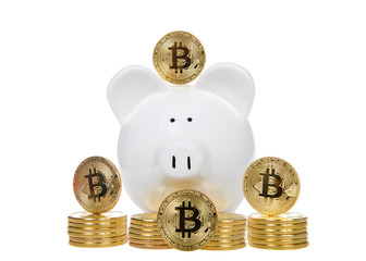 White piggy bank with bit coin physical coins stacked in front of it and four up on end showing B for bitcoin design. Investing