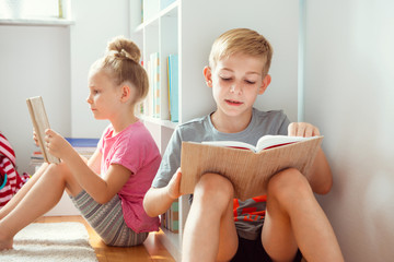 Happy children reading books on the floor at the school  library