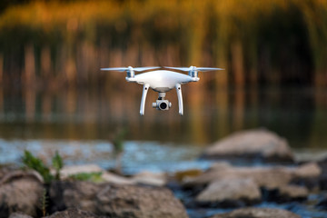 quadcopter drone flying with a camera over a lake.