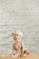 Wall Mural - Baby chef - indoor portrait of an adorable baby with chef hat and wooden spoon