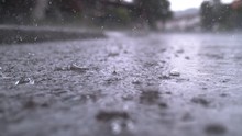 SLOW MOTION CLOSE UP: Autumn Rain Water Drops Falling Into Big Puddle On Asphalt, Flooding The Street. Road Floods Due To The Heavy Rain In Wet Season. Raindrops Falling Down Onto Submerged Road