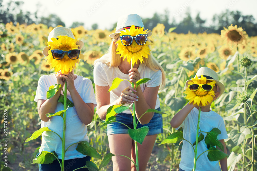 Mom and sons are walking around the field with sunflowers. A happy day.	 - obrazy, fototapety, plakaty 