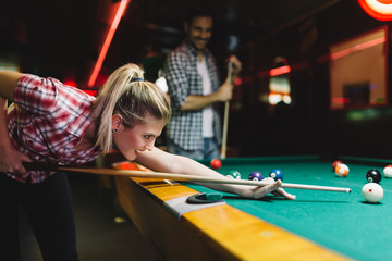 Young attractive woman playing pool in bar