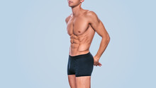 Image Of Fitness Male Model In Black Underwear Showing His Abdominal Torso On A Blue Background. Portrait Of Sporty Healthy Strong Athletic Man With Sexy Abdomen Posing In Studio. Healthy Lifestyle