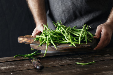 Canvas Print - Male hands holding raw green bean wooden cutting board Healthy vegetarian food