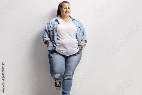 Cuadros en Lienzo Young overweight woman standing against a wall