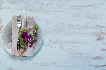 rustic table setting with purple flowers on light wooden table.