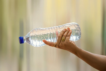  Water bottle in woman's hand on blurred green bokeh background