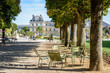 The Luxembourg garden in Paris, France, by a sunny summer morning with people biking, strolling or resting on metal lawn chairs and the Luxembourg palace, seat of the Senate in the background.