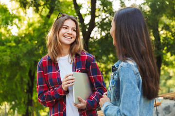 Wall Mural - Ladies students walking in the park talking with each other.