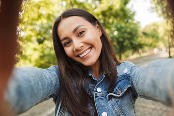 Canvas Print - Beautiful woman student walking in the park take a selfie by camera.