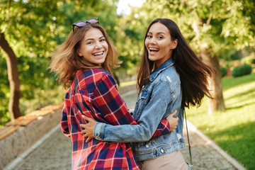 Wall Mural - Beautiful ladies students walking in the park looking camera.