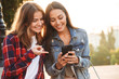 © Drobot Dean - Women friends students walking in the park using mobile phone.