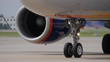 Landing gear and engine of jet airliner. Fuselage reflects taxiway marking