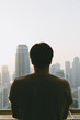 © TY Studio - Young man standing with his back facing a view of the city with skysrapers in Dubai