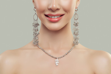 Wall Mural - Closeup of smiling woman lips and fashion jewelry. Silver necklace and earrings. Beauty and accessories.