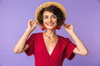 Pleased elegant woman in dress and straw hat posing