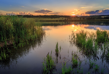 Sunset on the lake. The water reflects the setting sun and clouds.