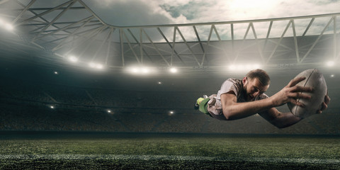 Wall Mural - Dirty rugby player catch the ball in flight on professional rugby stadium