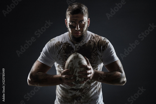 Fototapety Rugby  na-bialym-tle-brudny-gracz-rugby-z-pilka-do-rugby-na-ciemnym-tle