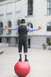 The clown juggles with small balls, standing on a large ball in the street of a European city