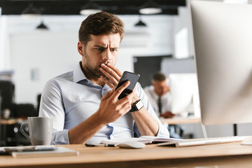 Poster - Shocked business man using smartphone and covering his mouth