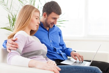 Wall Mural - Portrait of cheerful Couple on the couch using laptop