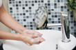 © DragonImages - Crop side view of woman washing hands with soapy foam in white sink in bathroom