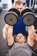 © Photocreo Bednarek - Senior man lifting weights assisted by gym instructor